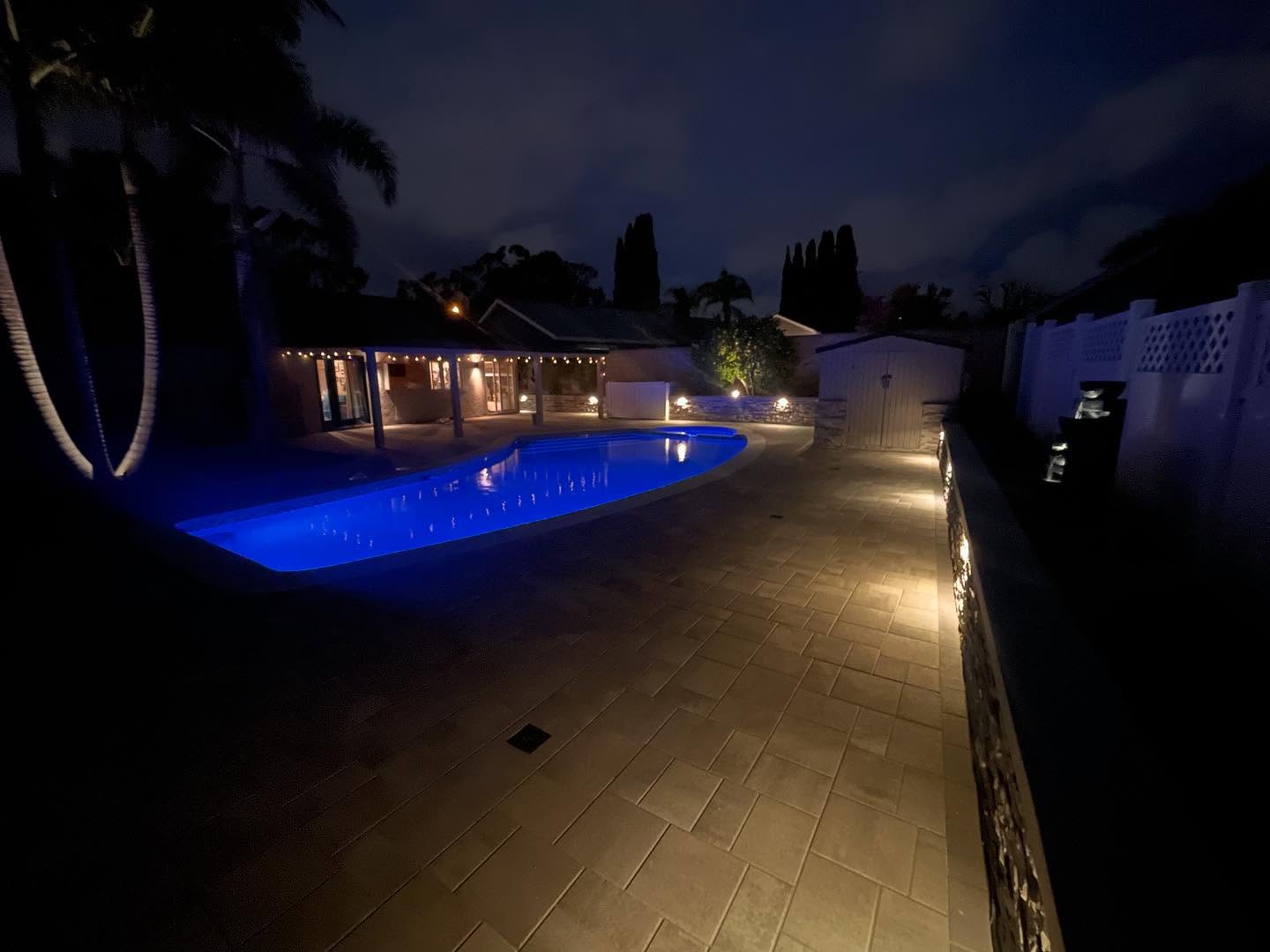 Paver pool deck with landscape lighting at night