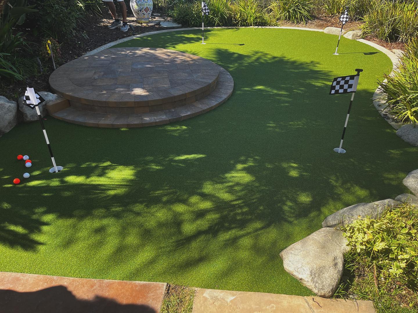 Backyard artificial turf putting green beside a paver patio